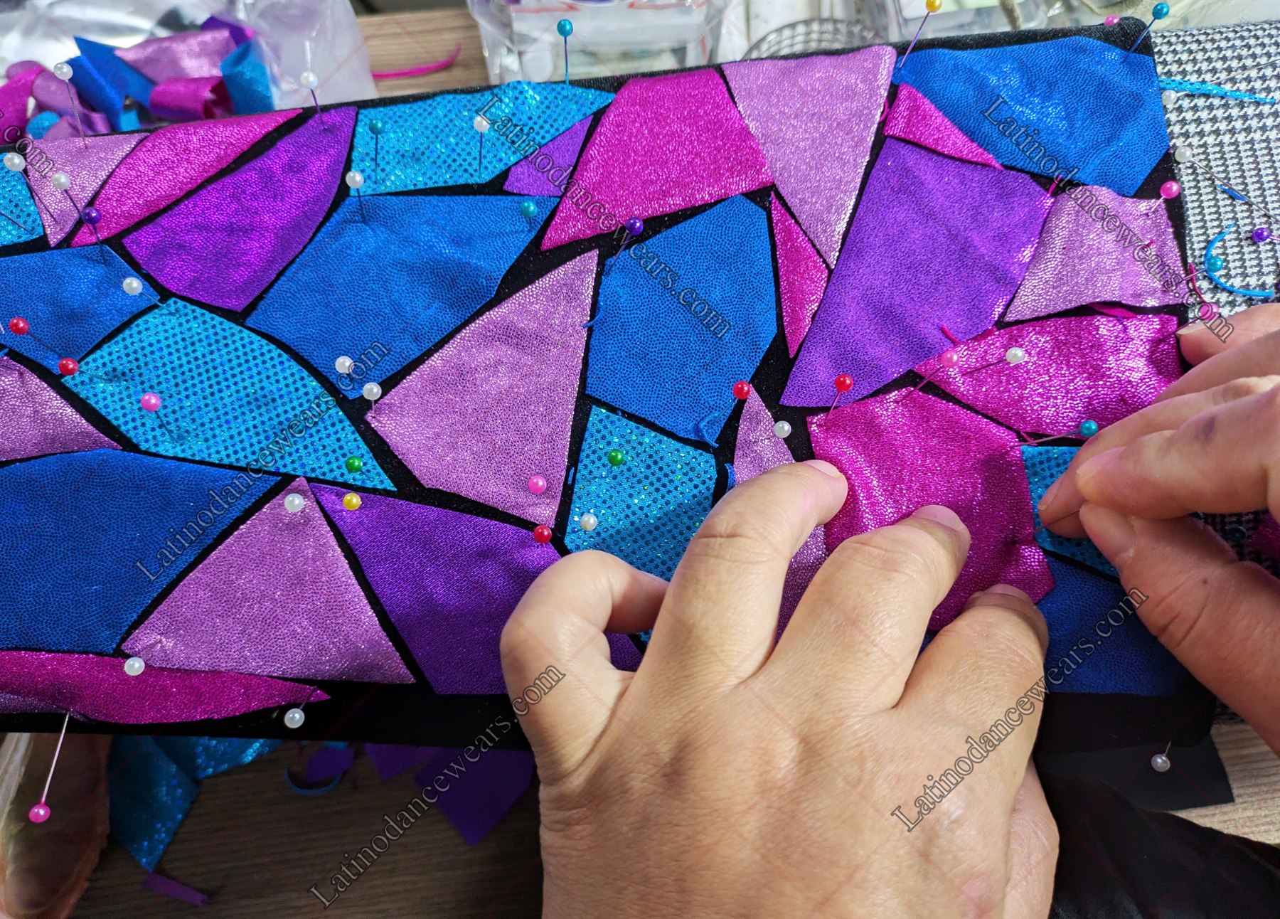Colourful fabric pieces being arranged and stitched by hand