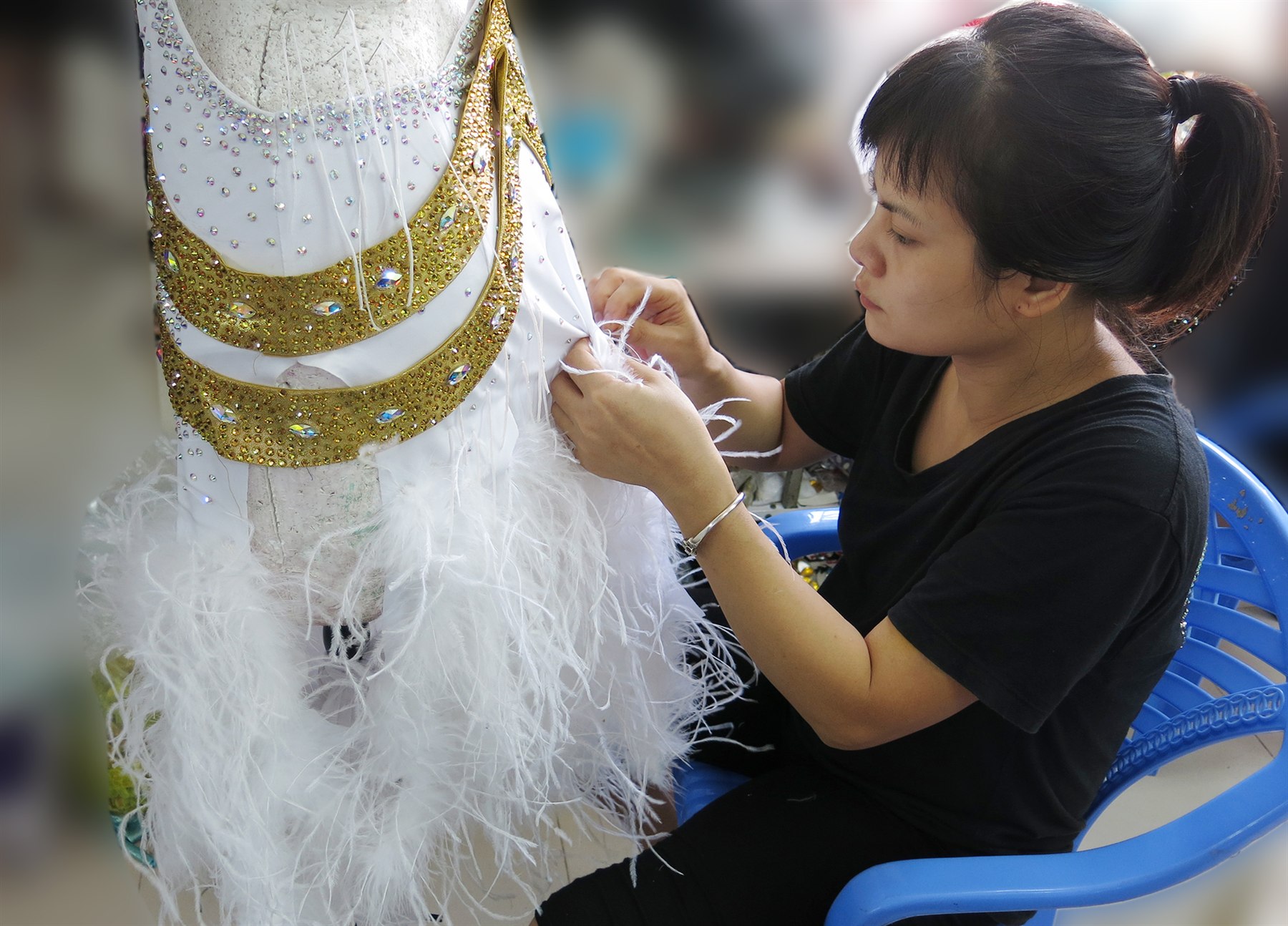Artisan hand-finishing a white and gold dance costume
